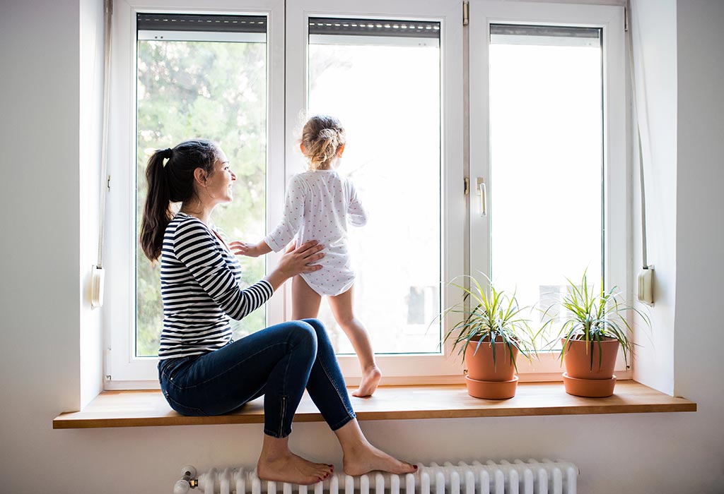 Mother with her little daughter looking out of window