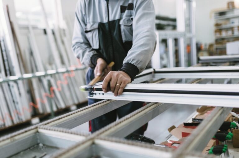 Handwerker klopft auf einem Aluminum Fenster